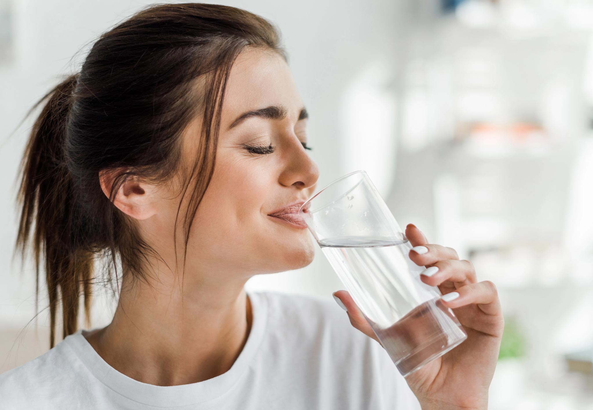 Woman enjoying a glass of clean drinking water, highlighting the importance of safe tap water and plumbing services for health.